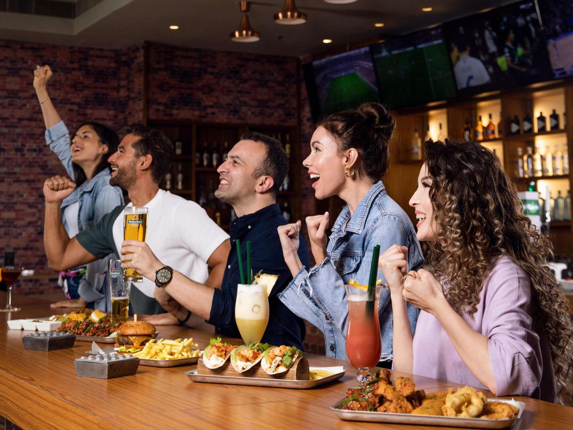 Hotel Hilton Ad Dawhah Esterno foto People watching a game at a sports bar